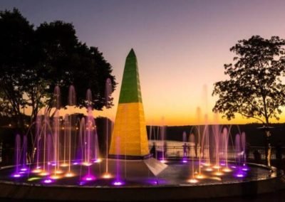 chafariz verde e amarelo com jatos de água iluminados ao por do sol em Foz do Iguaçu