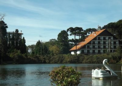 lago com pedalinho em formato de cisne branco e hotel ao fundo em Gramado