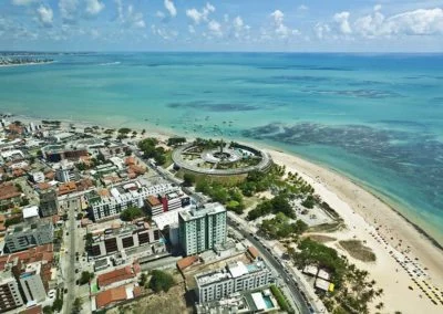 vista aérea da praia de João Pessoa com a cidade na beira do mar de coloração esverdeada