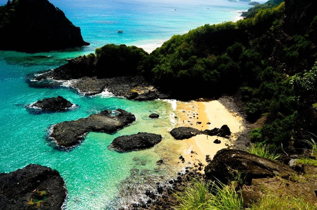 morro com vegetação e pedras dentro do mar em Fernando de Noronha