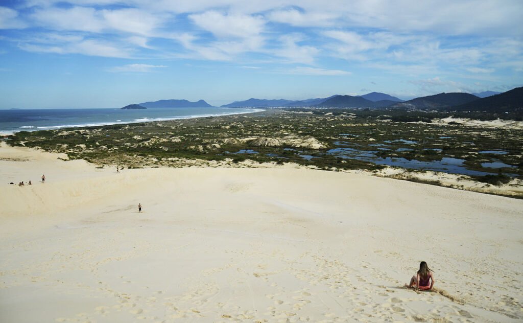 mulher fazendo sandboard nas dunas da Praia da Joaquina em Florianópolis